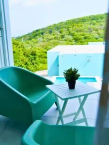 Terrace chairs and table with a view of the pool and green hill