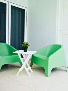 Two green chairs and a small table on the porch