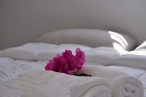 Fresh towels with a pink bougainvillea flower on the bed