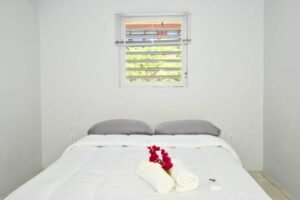 Villa bed with fresh towels and a red flower